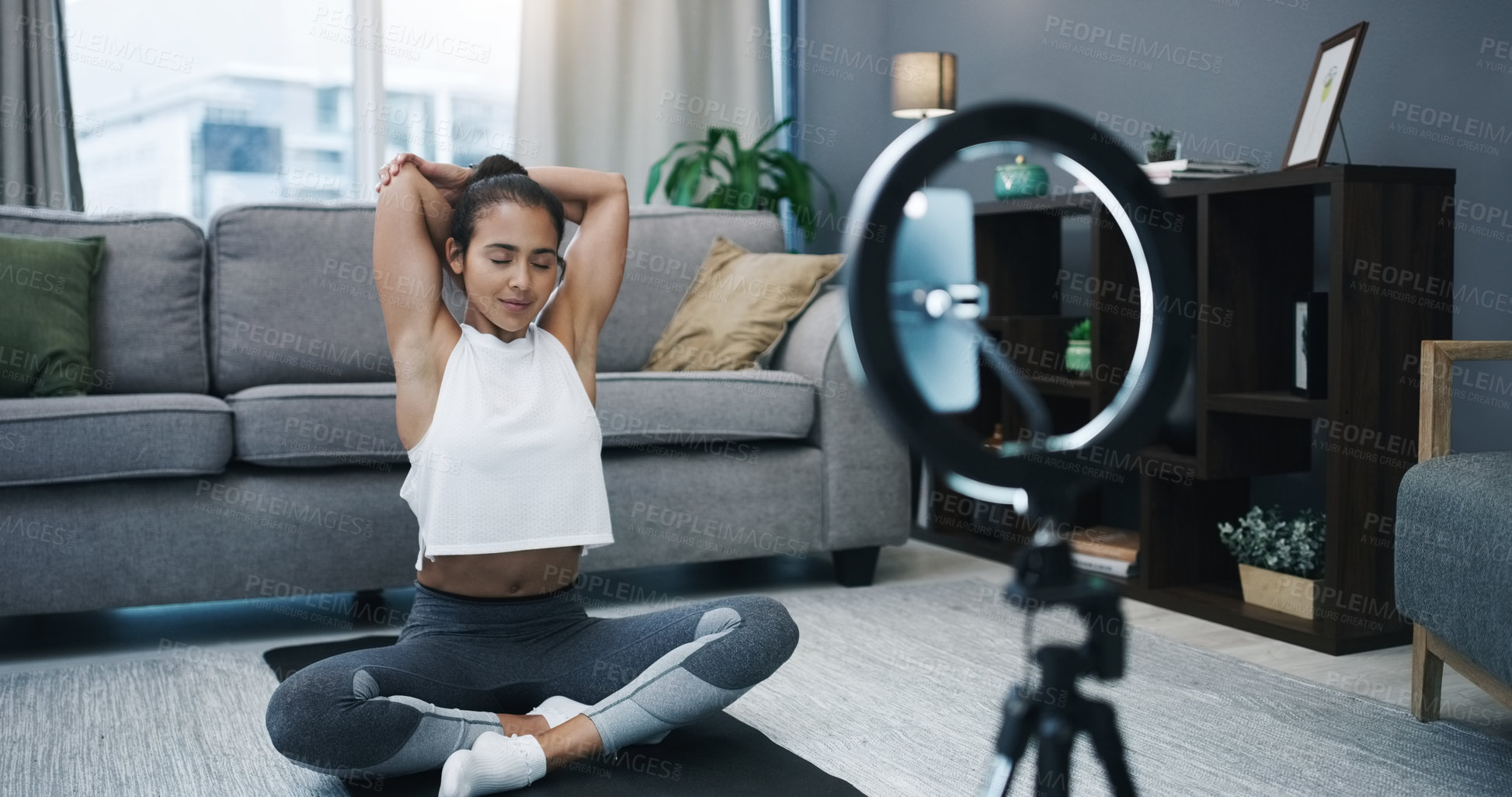 Buy stock photo Shot of a woman recording herself with a ring light and her cellphone while exercising at home