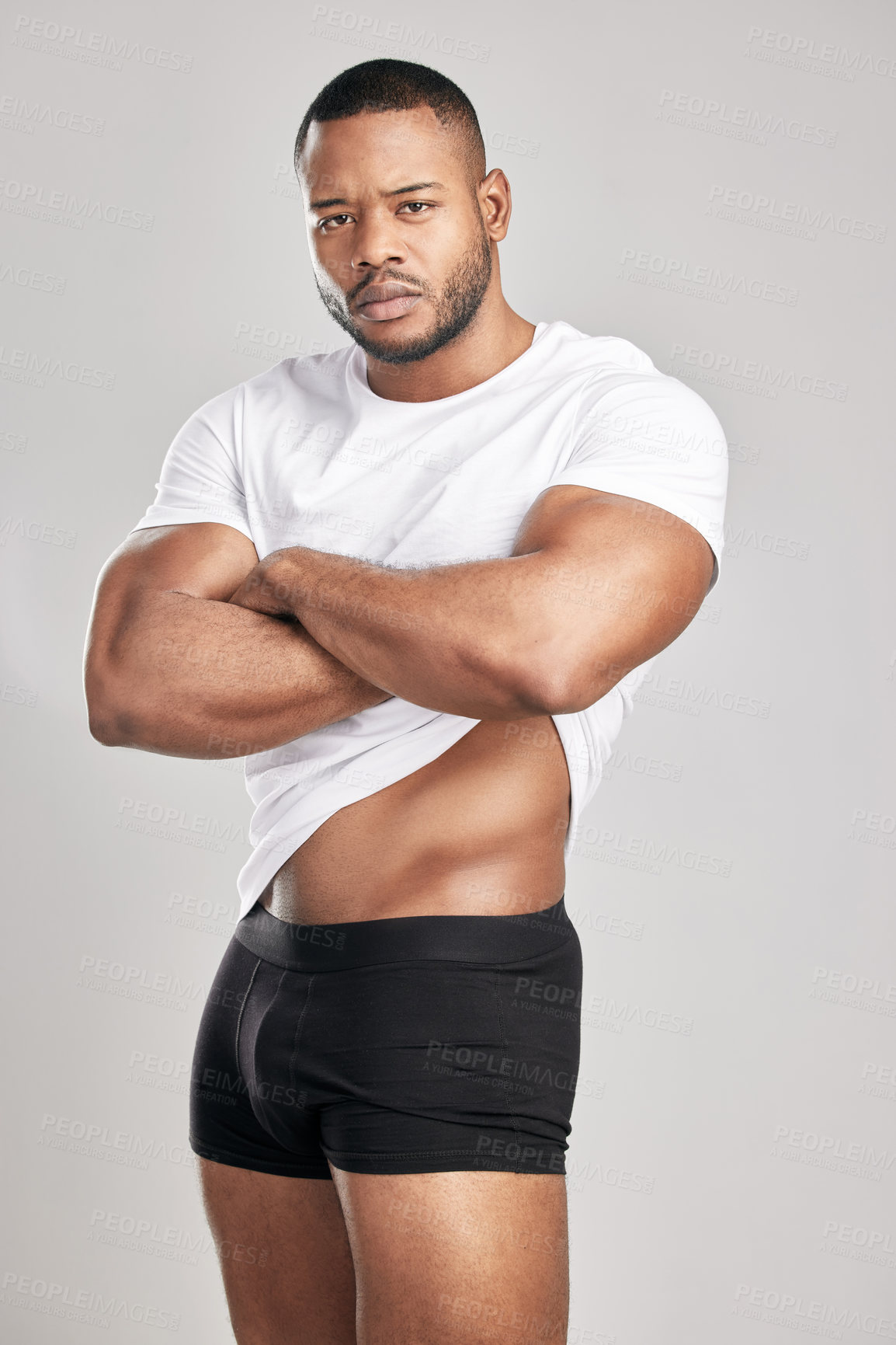 Buy stock photo Studio shot of a young muscular man posing against a grey background