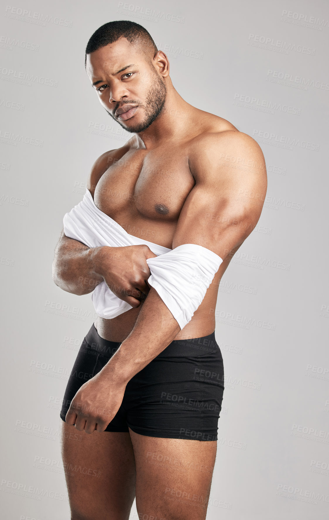 Buy stock photo Portrait, pride and African man with shirt in studio for wellness, pride and fitness in underwear on backdrop. Male athlete, workout and bodybuilder on grey background with strength for healthcare 