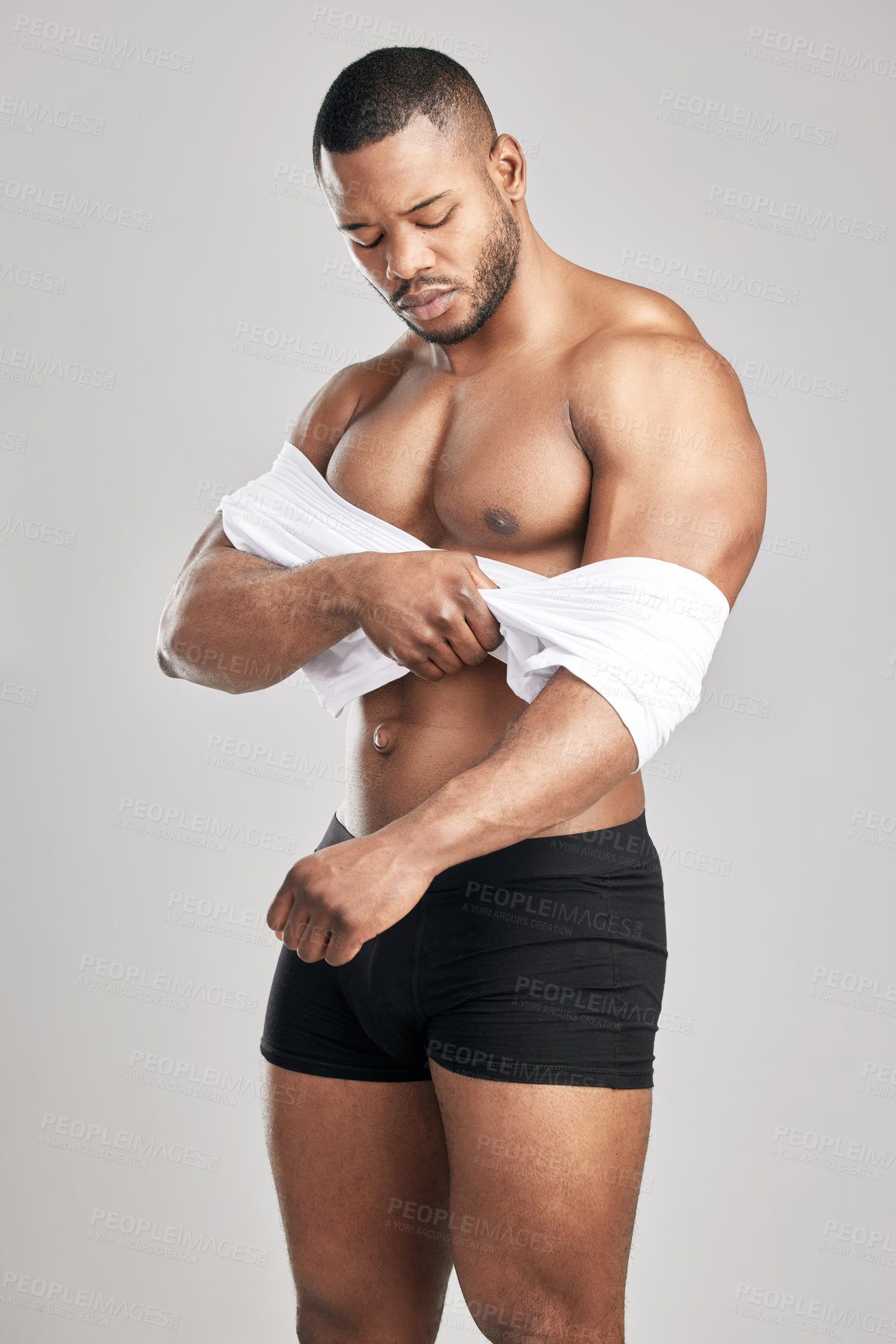 Buy stock photo Studio shot of a young muscular man posing against a grey background