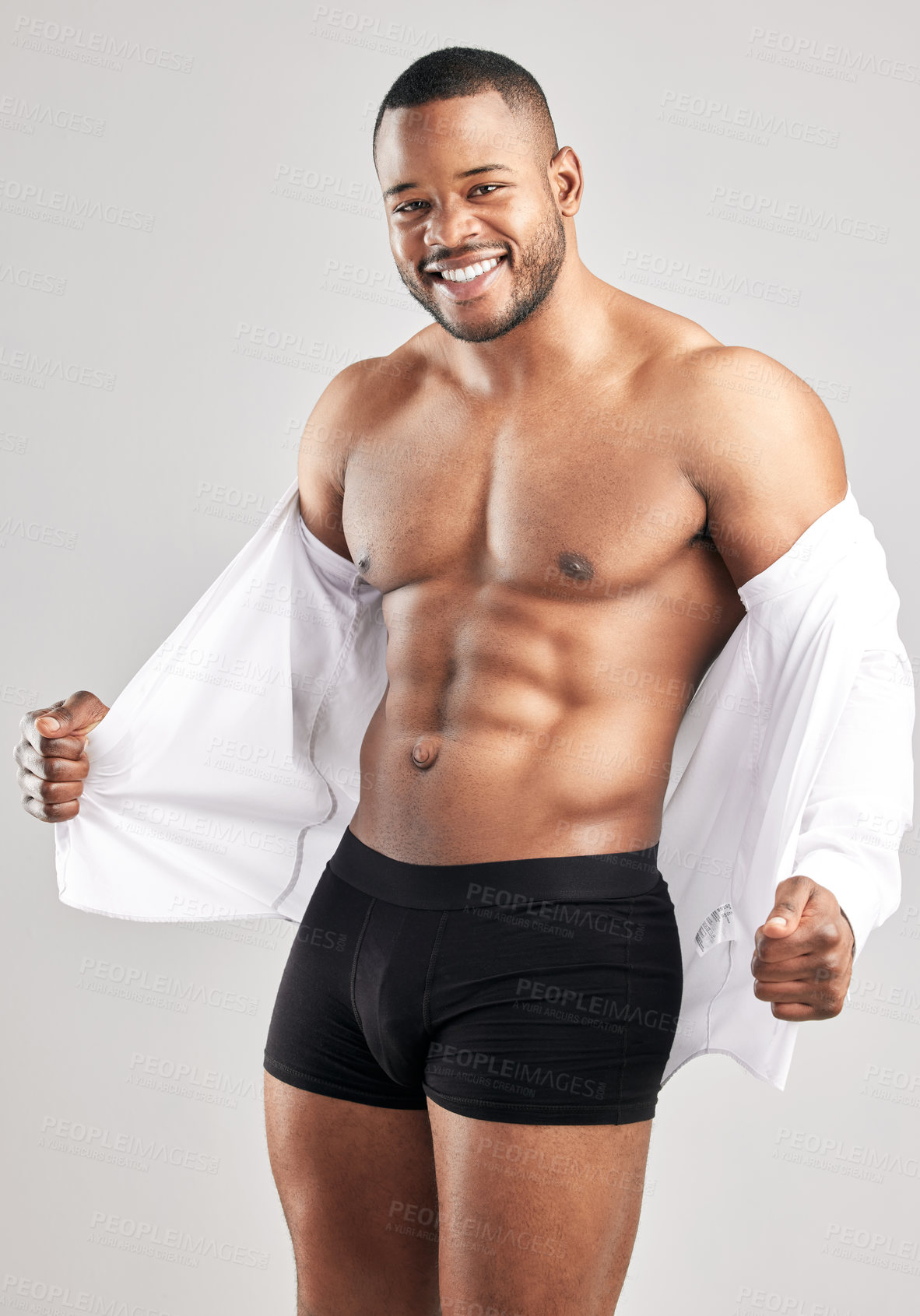 Buy stock photo Studio shot of a young muscular man posing against a grey background