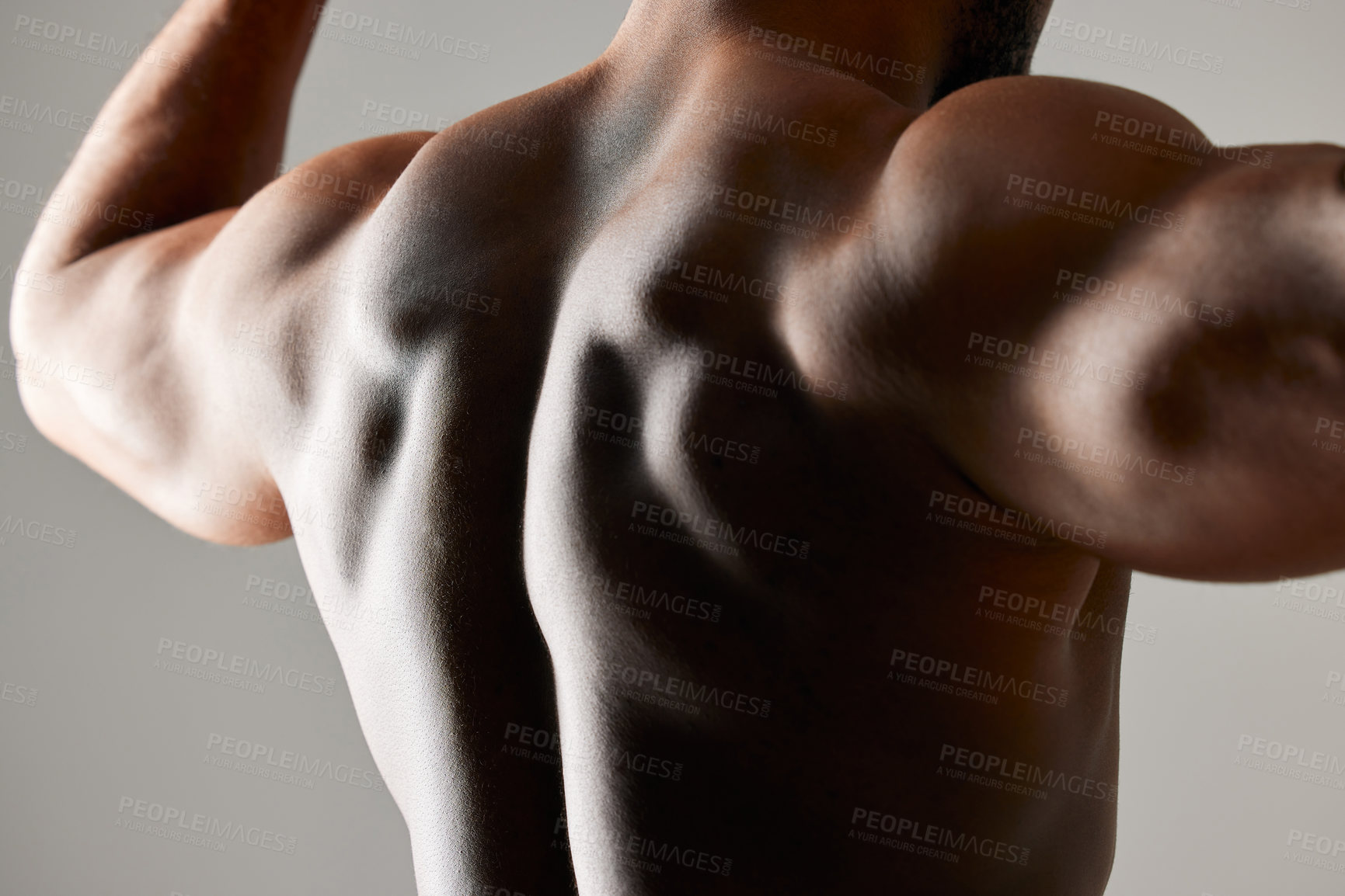 Buy stock photo Studio shot of a unrecognizable male flexing his back muscles against a grey background