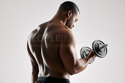 Buy stock photo Studio shot of an young man working out with a dumbbell against a grey background