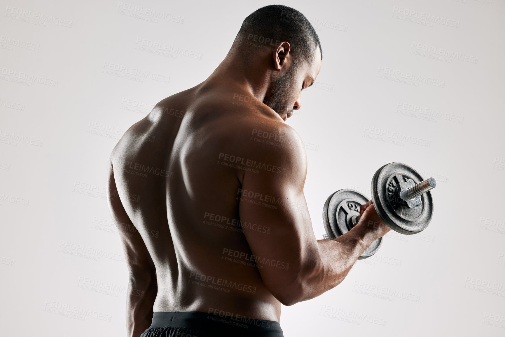 Buy stock photo Studio shot of an young man working out with a dumbbell against a grey background