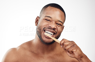 Buy stock photo Studio portrait of a handsome young man brushing his teeth against a white background