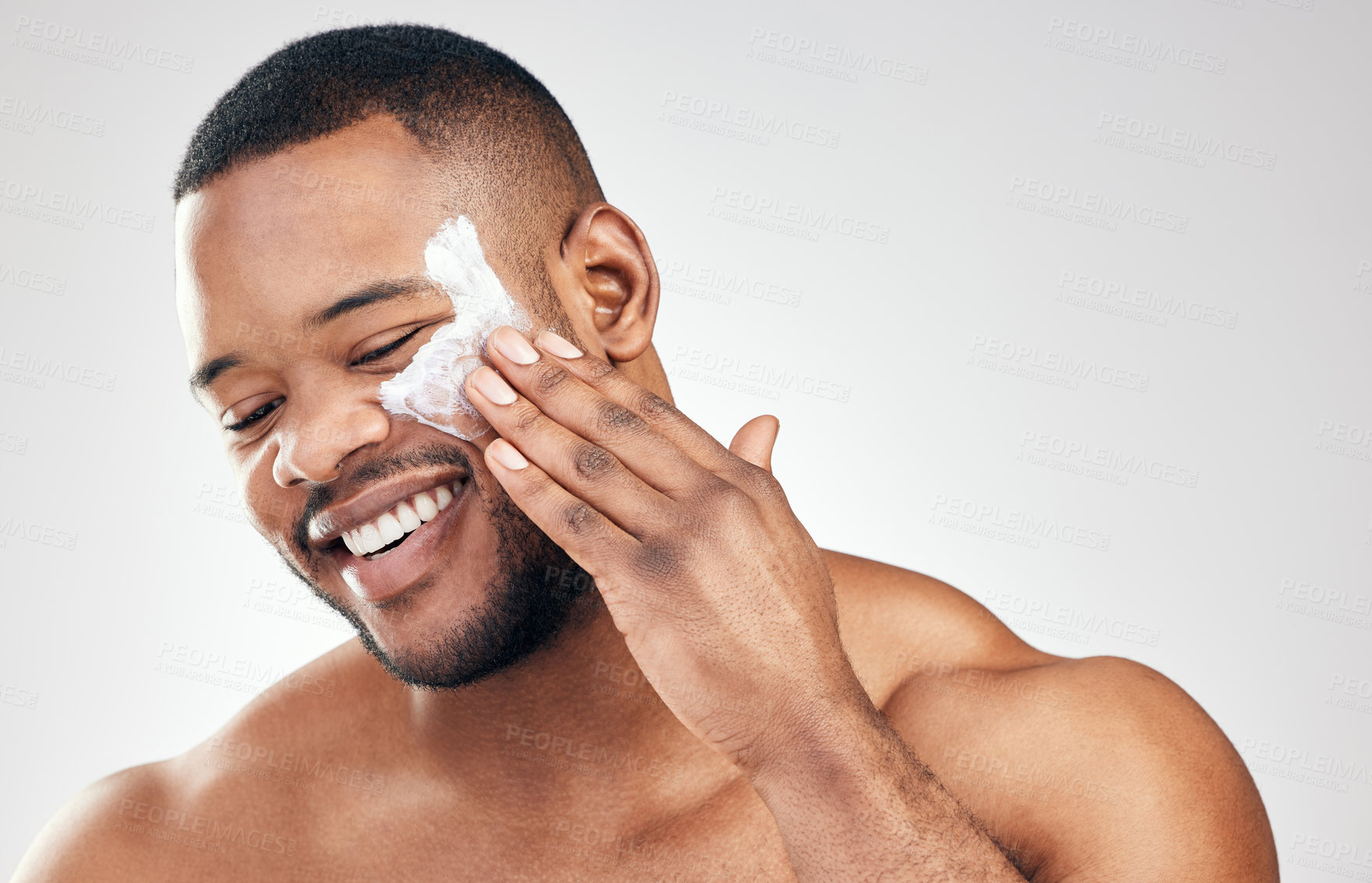 Buy stock photo Studio shot of a handsome young man applying moisturiser to his face against a white background