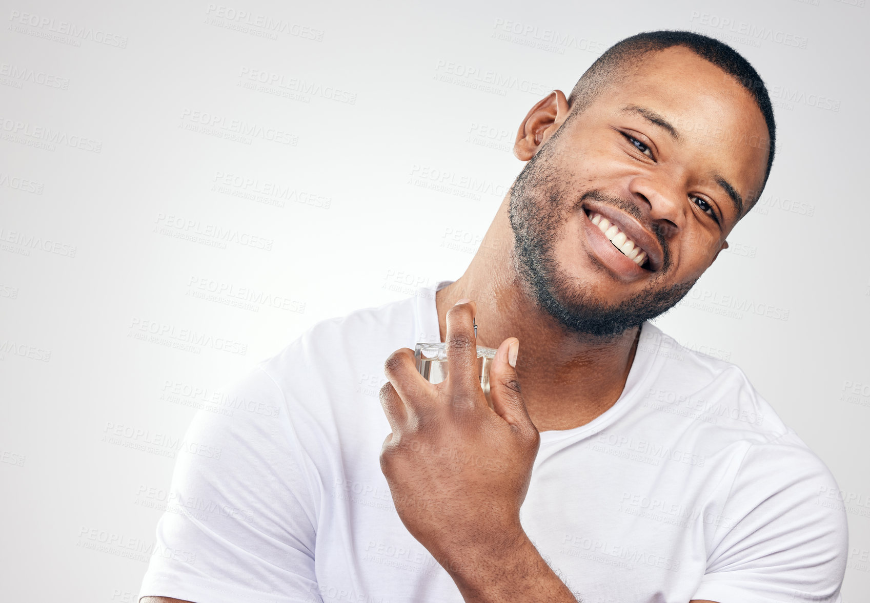 Buy stock photo Studio portrait of a handsome young man spraying perfume on himself against a white background