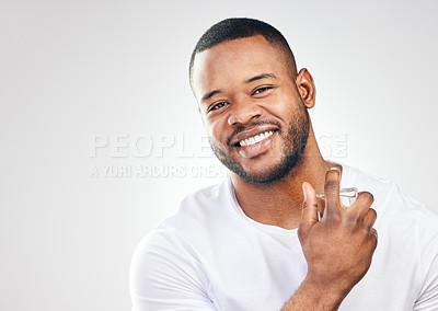 Buy stock photo Studio portrait of a handsome young man spraying perfume on himself against a white background