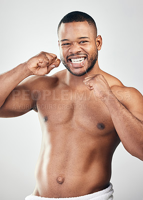 Buy stock photo Studio portrait of a handsome young man flossing his teeth against a white background