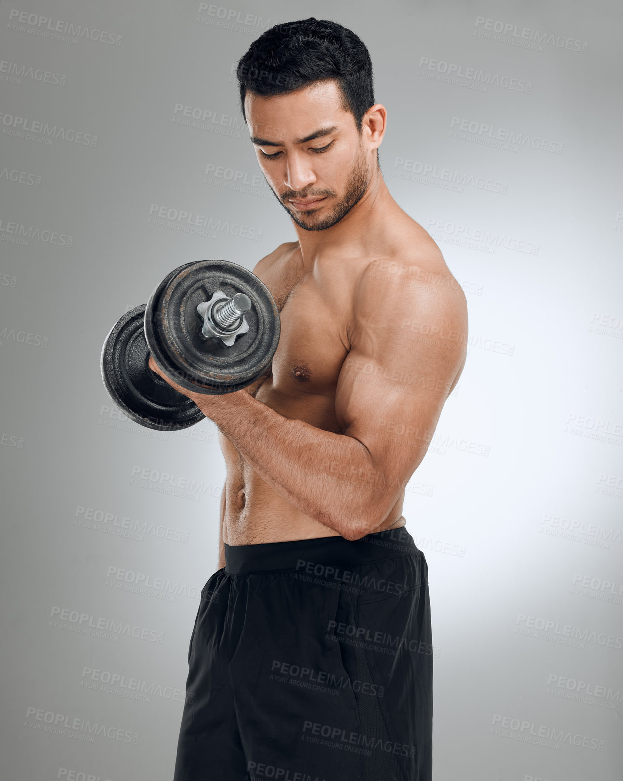 Buy stock photo Shot of a man working out with weights while standing against a grey background
