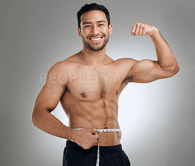 Buy stock photo Studio shot of a man flexing his muscles while measuring his waist