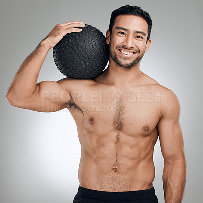 Buy stock photo Shot of an athletic young man posing against a grey background while holding a water bottle and a medicine ball