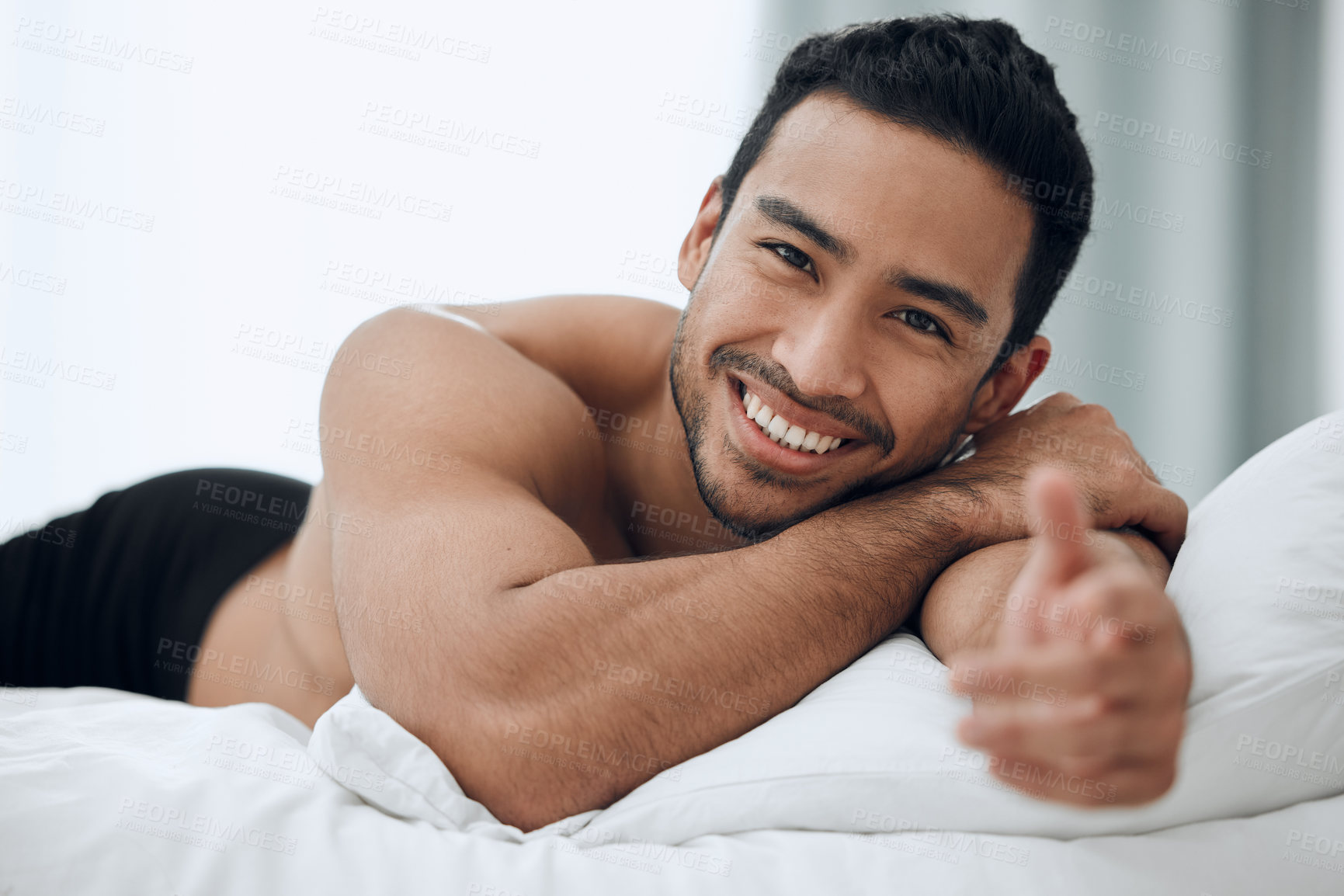 Buy stock photo Hand welcome, portrait and man lying in bed in morning for relax, invitation or gesture in bedroom. Smile, body and Asian person with muscles for resting, confidence or weekend break in home