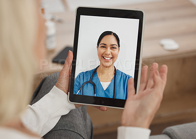 Buy stock photo Shot of a mature woman using a digital tablet to have a video call with her doctor on the sofa at home