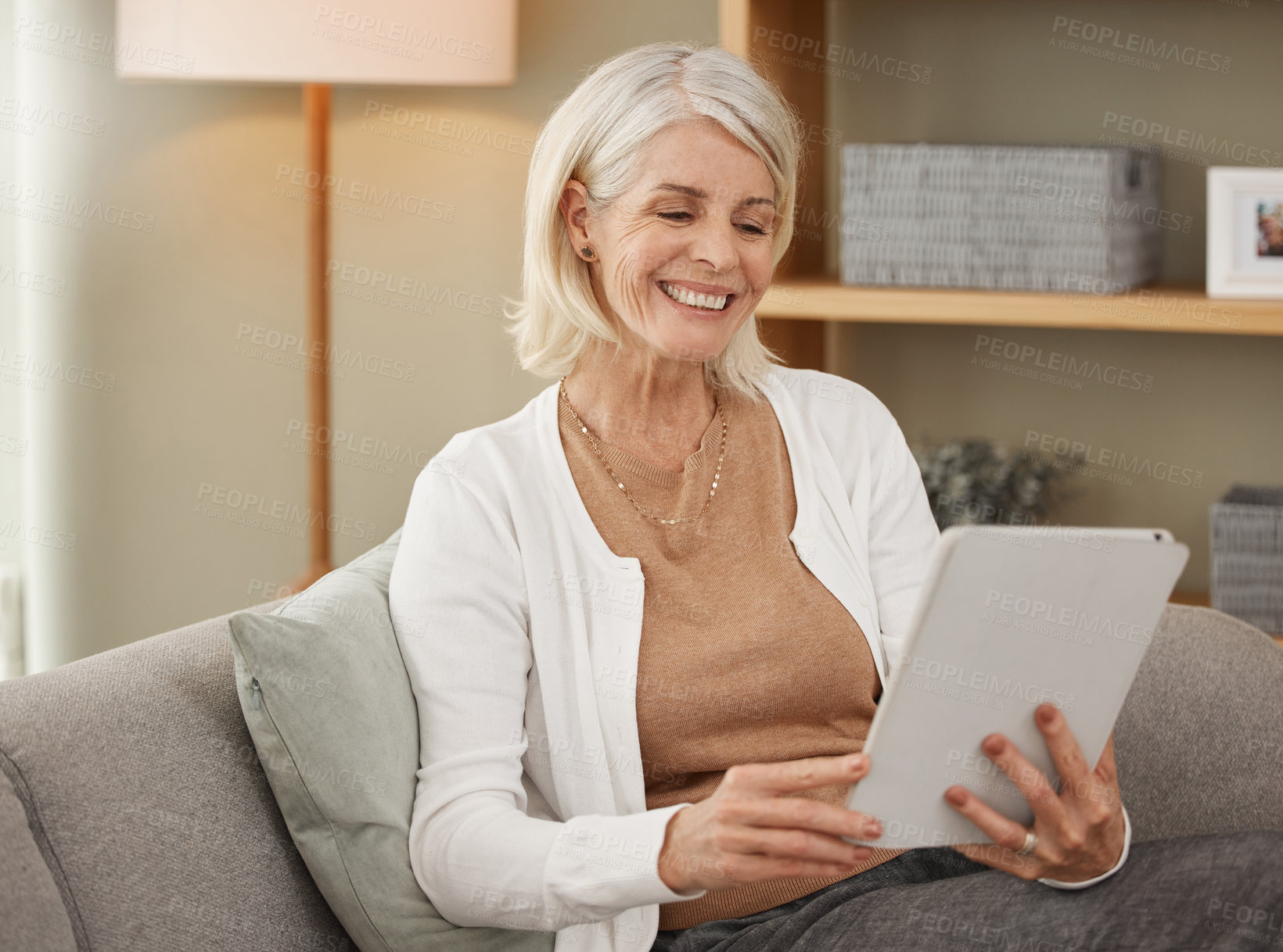 Buy stock photo Shot of a mature woman using a digital tablet on the sofa at home