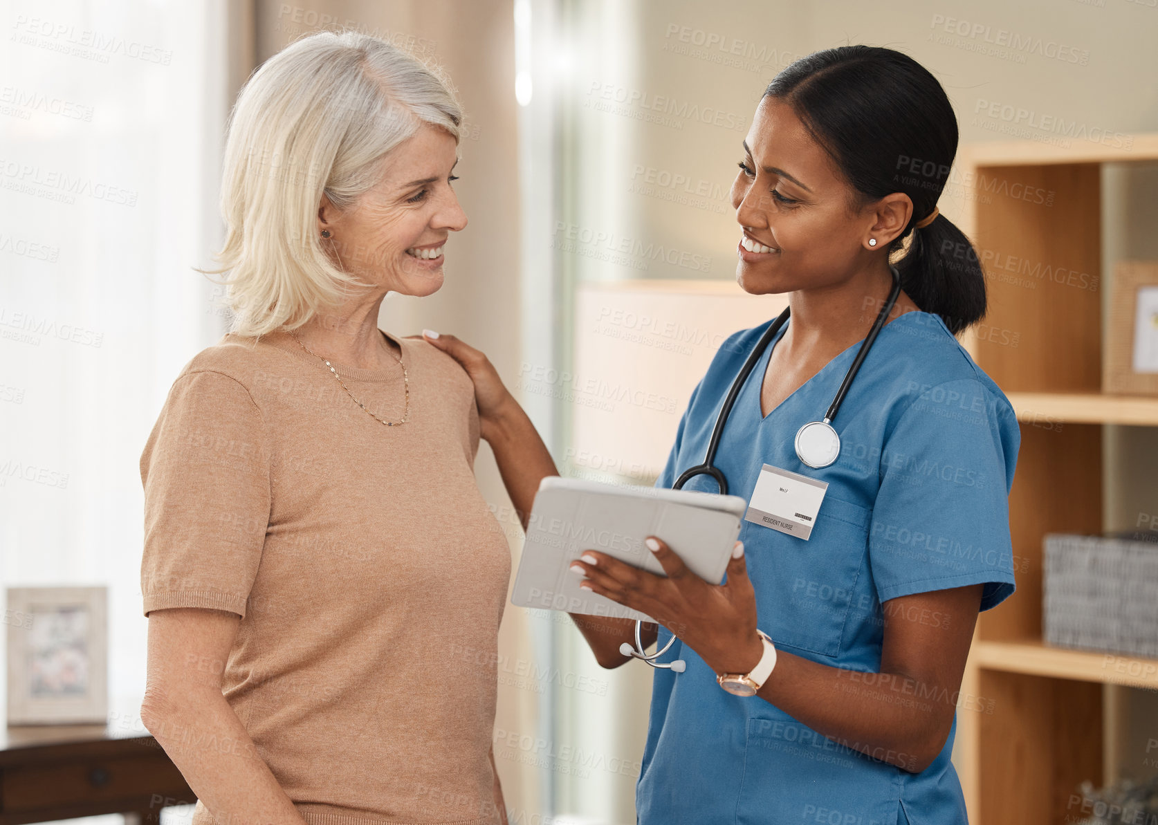 Buy stock photo Shot of a doctor using a digital tablet during a consultation with a senior woman at home