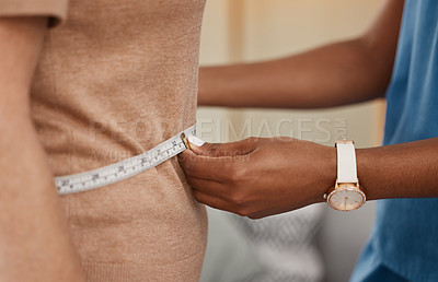 Buy stock photo Shot of a doctor using a measuring tape on a senior woman’s stomach during a consultation at home