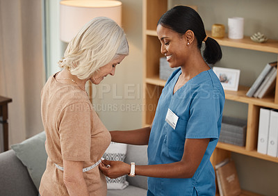 Buy stock photo Shot of a doctor using a measuring tape on a senior woman’s stomach during a consultation at home
