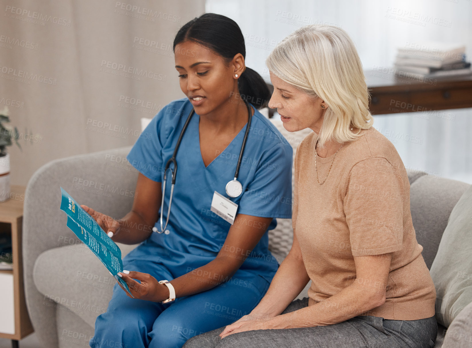 Buy stock photo Shot of a doctor reading a pamphlet about Covid-19 on the sofa at home