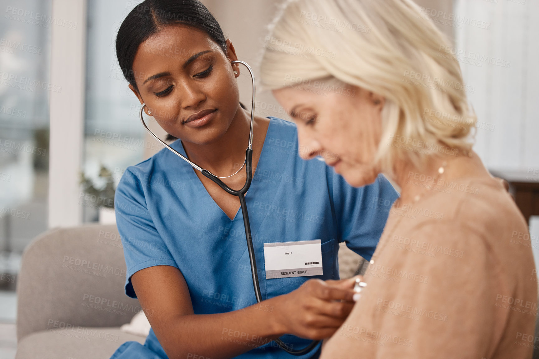 Buy stock photo Shot of a doctor examining a senior woman with a stethoscope at home