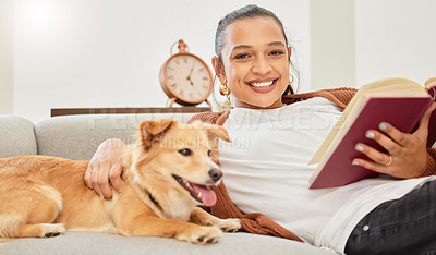 Buy stock photo Portrait of a beautiful young woman reading a book on the couch with her dog at home
