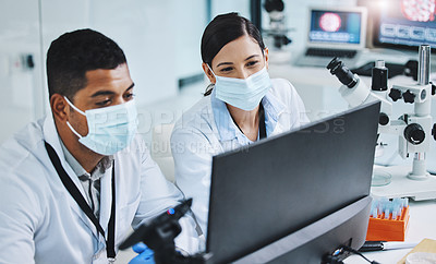 Buy stock photo Shot of two young researchers using a computer in a laboratory