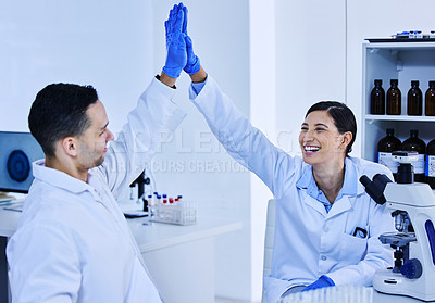 Buy stock photo Cropped shot of two young scientists high fiving while working in their lab