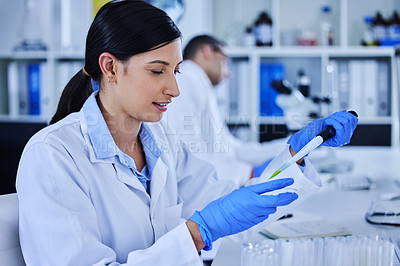 Buy stock photo Cropped shot of an attractive young female scientist working in her lab with a colleague in the background