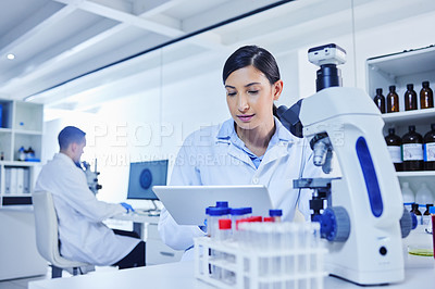 Buy stock photo Cropped shot of an attractive young female scientist working with a microscope and tablet in her lab