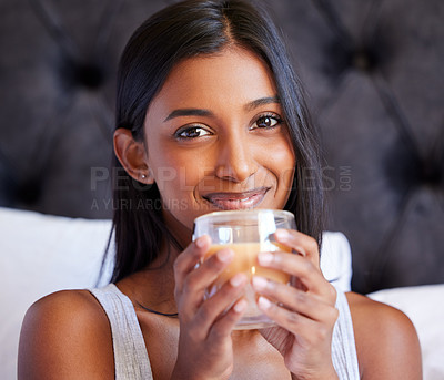 Buy stock photo Shot of a young woman drinking a hot beverage while sitting on her bed