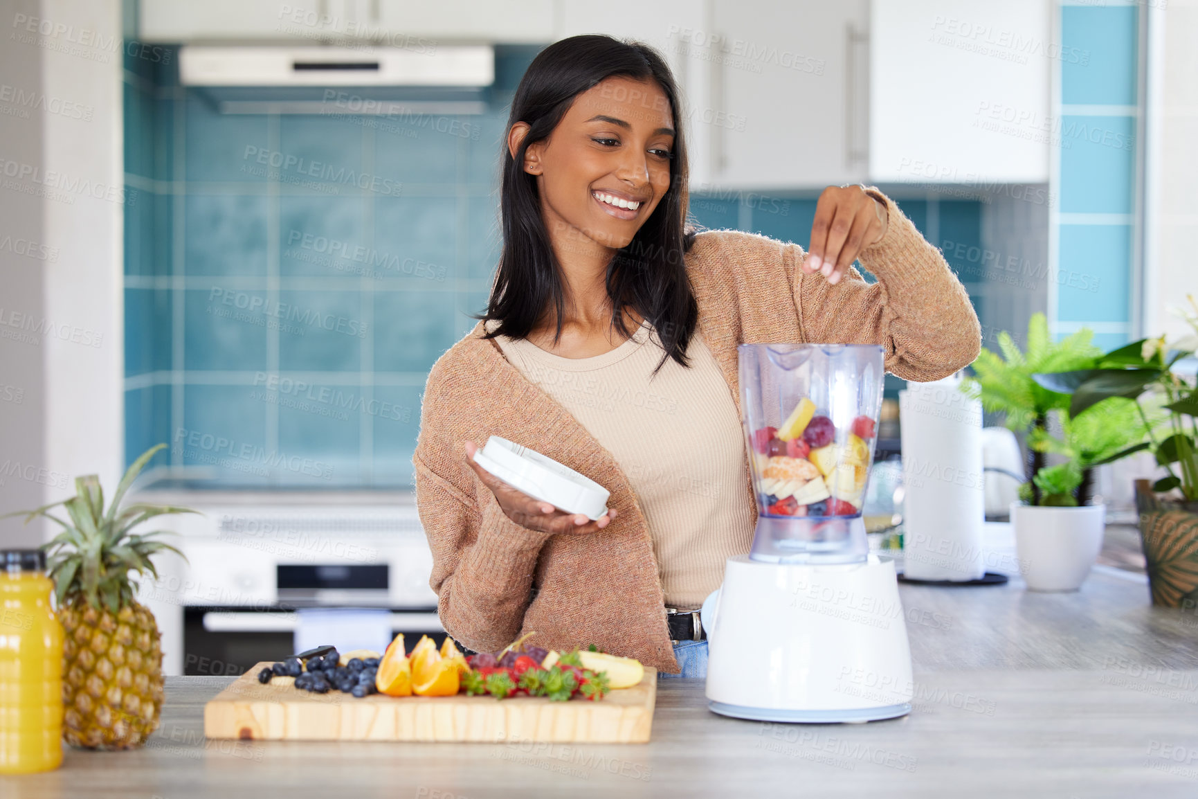 Buy stock photo Shot of a young woman preparing a healthy smoothie at home