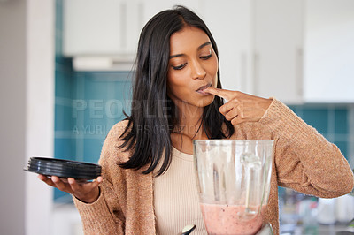 Buy stock photo Shot of a young woman preparing a healthy smoothie at home