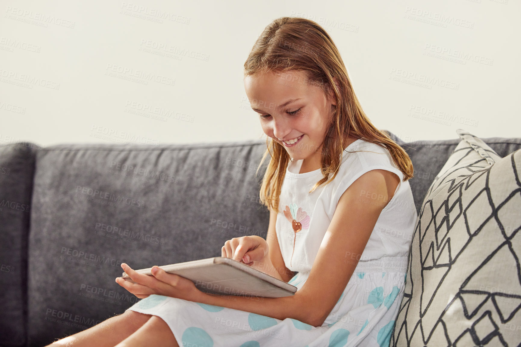 Buy stock photo Child, tablet and smile on sofa for game, learning and development for online movies or virtual education. Cute girl, happy or digital tech in lounge for relax, video or streaming internet in home