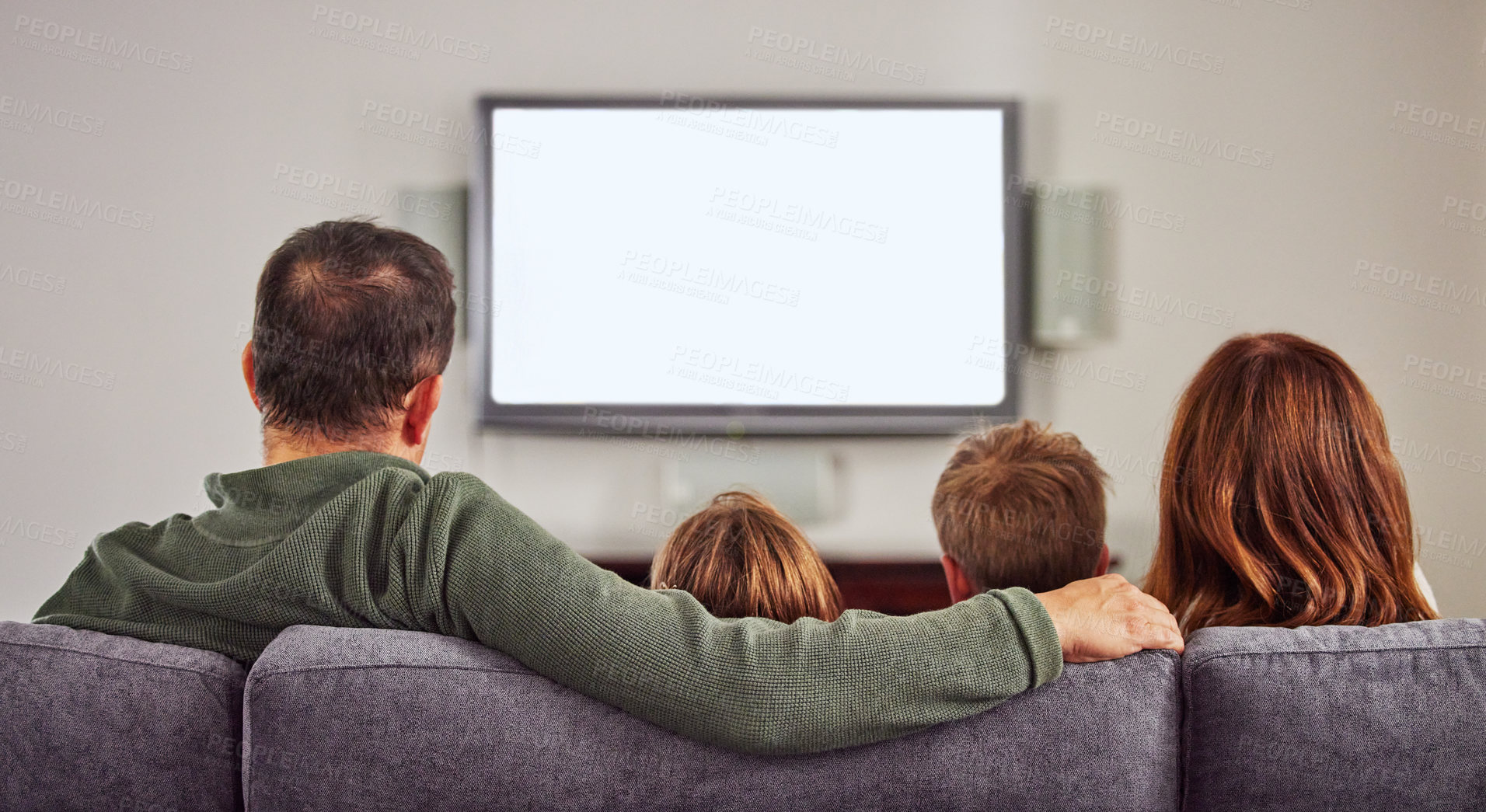 Buy stock photo Shot of an unrecognizable family sitting on the sofa at home together and bonding while watching tv