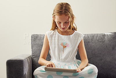 Buy stock photo Typing, home and girl on sofa, tablet and digital app for games, social media and online cartoon. Apartment, child development or kid with tech, internet or connection to reading ebook and network