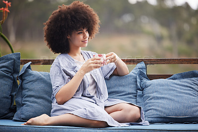 Buy stock photo Shot of an attractive young woman relaxing with a cup of coffee outside on the patio