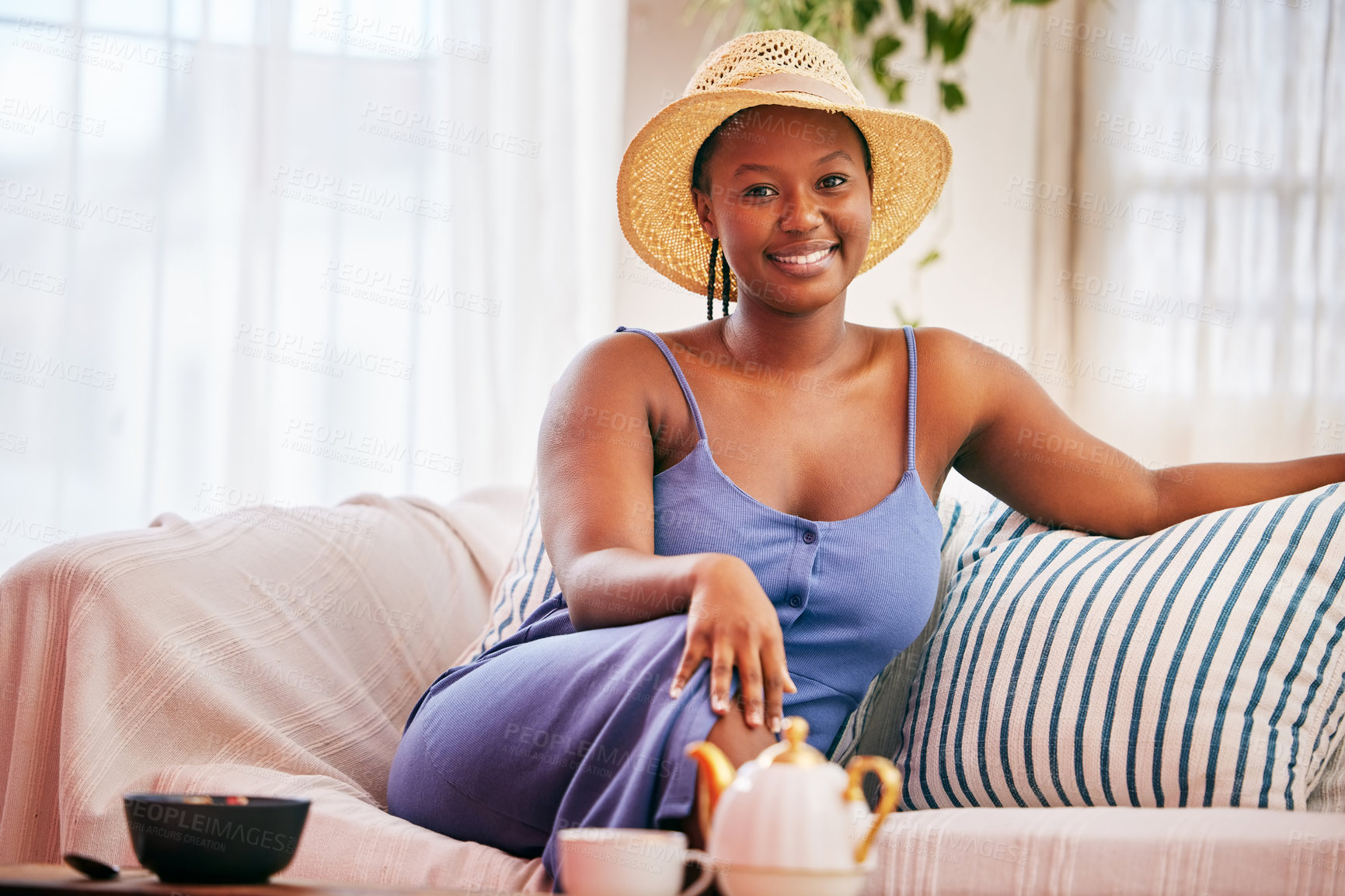 Buy stock photo Portrait of a young beautiful woman wearing a sunhat while relaxing on the sofa at home