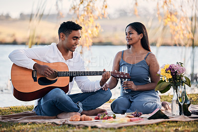 Buy stock photo Picnic, couple and man with guitar for playing music, singing and romantic date for anniversary. Love, woman and partner in park for relax, celebrate and bonding in relationship with snack in nature