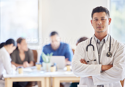 Buy stock photo Shot of a young male doctor standing with his arms crossed in an office at work