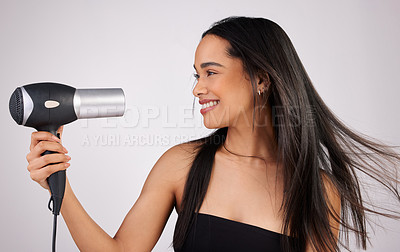 Buy stock photo Shot of a young woman holding a hairdryer while standing against a grey background