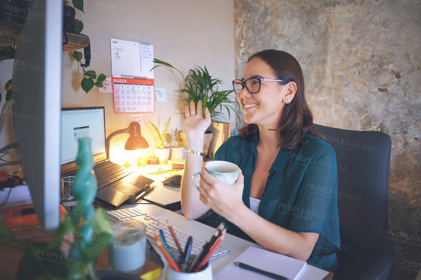 Buy stock photo Shot of an attractive young woman sitting alone and using her computer for a video chat while working from home