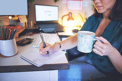 Buy stock photo Cropped shot of an unrecognizable woman sitting and enjoying a cup of coffee while writing notes in her home office