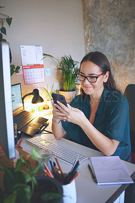 Buy stock photo Shot of an attractive young woman sitting alone and using her cellphone to work from home