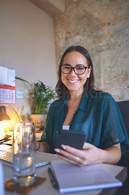 Buy stock photo Shot of an attractive young woman sitting alone and using her cellphone to work from home