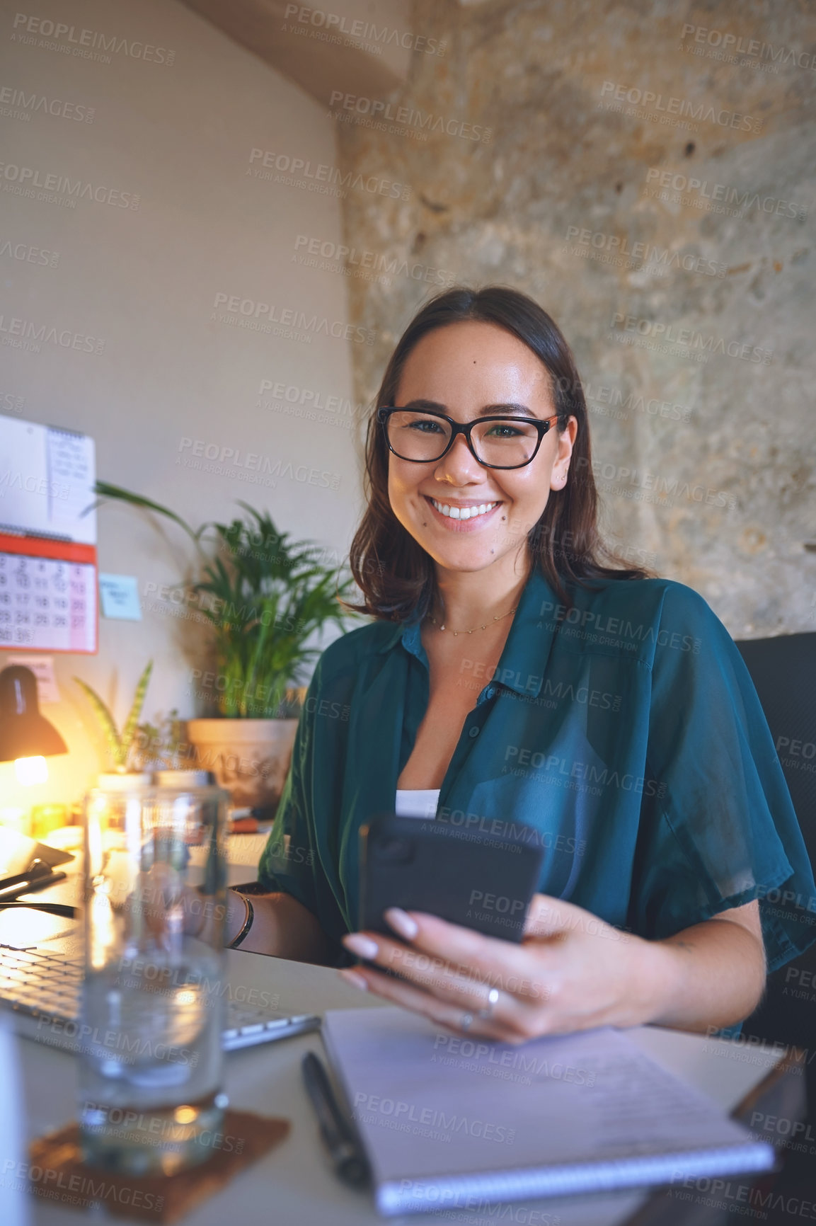 Buy stock photo Shot of an attractive young woman sitting alone and using her cellphone to work from home