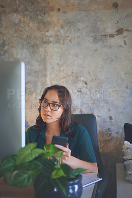 Buy stock photo Shot of an attractive young woman sitting alone and looking contemplative while using technology to work from home