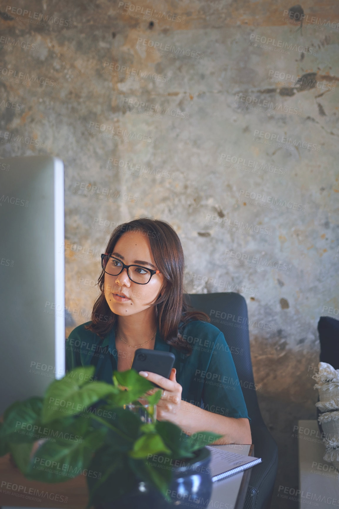 Buy stock photo Shot of an attractive young woman sitting alone and looking contemplative while using technology to work from home