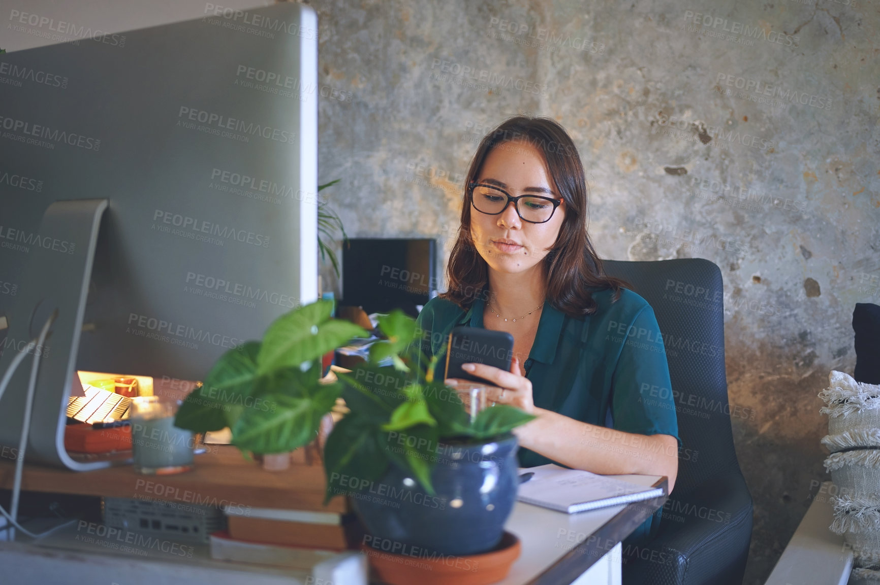 Buy stock photo Shot of an attractive young woman sitting alone and using her cellphone while working from home