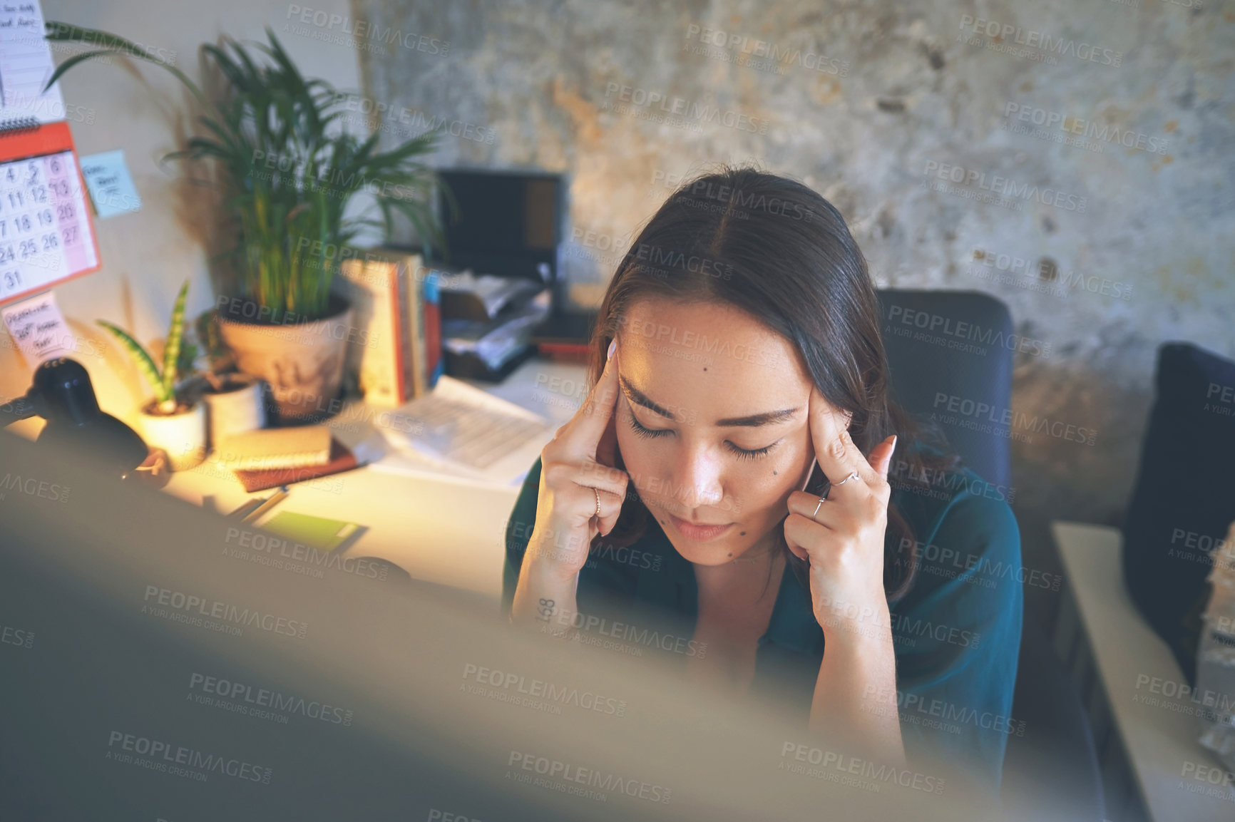 Buy stock photo Shot of an attractive young woman sitting alone and suffering from a headache while working from home