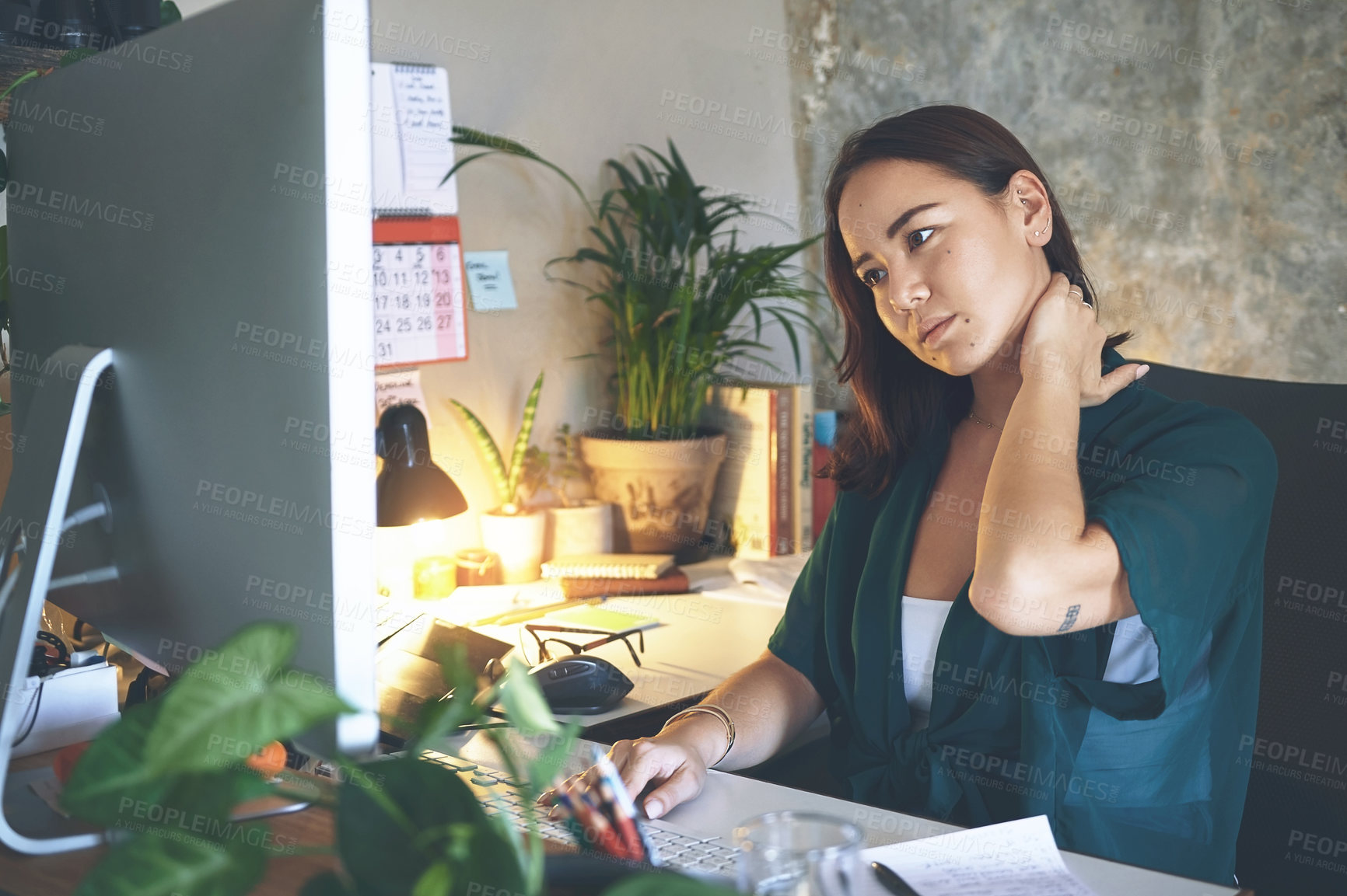 Buy stock photo Shot of an attractive young woman sitting alone and suffering from neck ache while working from home